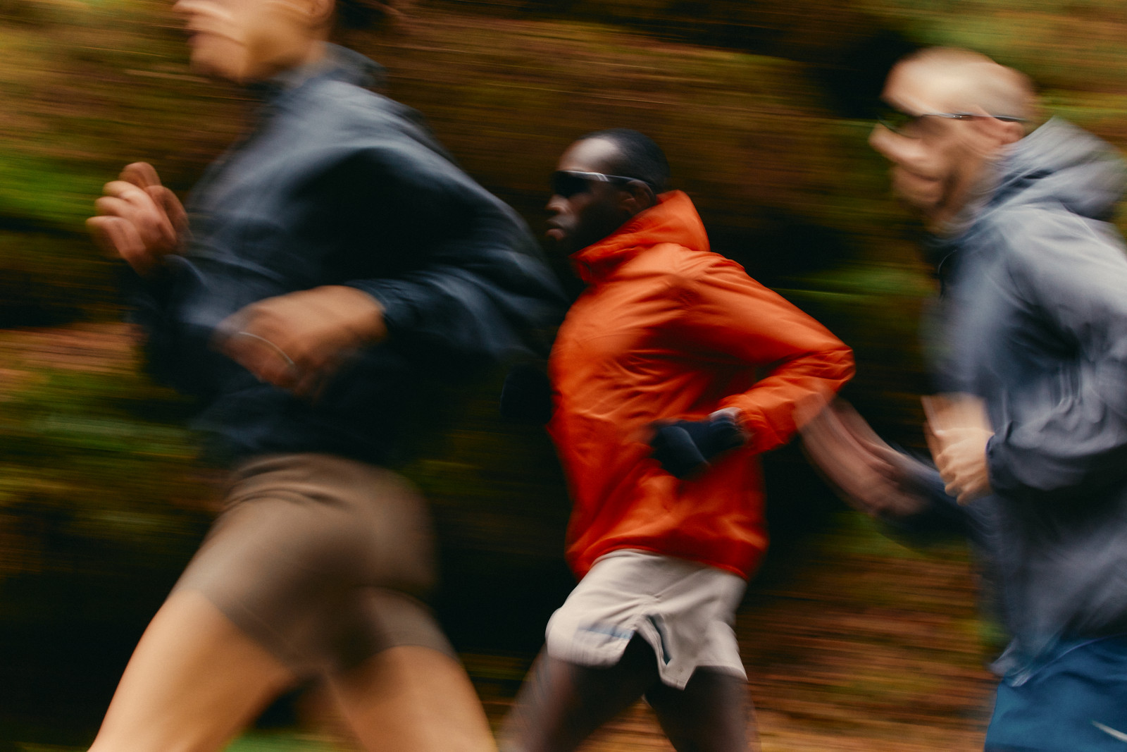 Runners in motion with a runner in an orange jacket at center